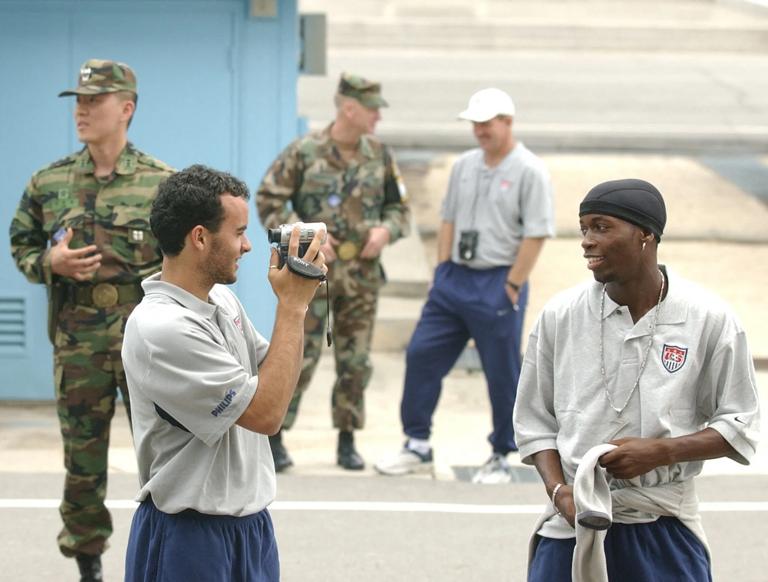 Landon Donovan (L) uses a video camera to record his teammate DaMarcus Beasley (R) as he and other teammates of the US national soccer team visit the de-militarized zone in Panmunjon 31 May 2002. Reyna and most of the team visited the zone marking the frontier between North and South Korea some 50 miles north of Seoul. The US soccer squad will face Portugal, South Korea and Poland in the first round of the 2002 FIFA Korea-Japan World Cup.   AFP PHOTO    Roberto SCHMIDT (Photo by ROBERTO SCHMIDT / AFP) (Photo by ROBERTO SCHMIDT/AFP via Getty Images)