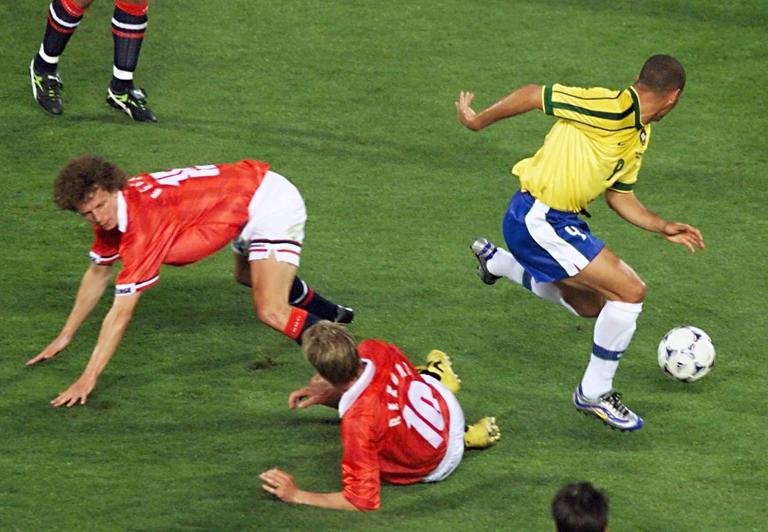 Brazilian forward Ronaldo (R) passes by Norwegian defender Dan Eggen (L) and midfielder Kjetil Rekdal (#10) as they fall down 23 June at the Stade Velodrome in Marseille, south of France, during the 1998 Soccer World Cup Group A first round match between Brazil and Norway.
(ELECTRONIC IMAGE) AFP PHOTO   GEORGES GOBET (Photo by GEORGES GOBET / AFP) (Photo by GEORGES GOBET/AFP via Getty Images)          